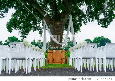Beautiful wedding ceremony setup with elegant white folding chairs in a scenic park setting 121446465