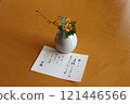 A letter from the innkeeper and a small vase with orange flowers 121446566