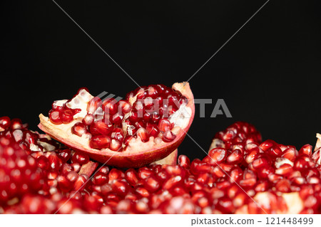 Pomegranate background, lots of peeled pomegranates and seeds, black background 121448499