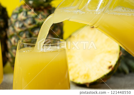 Pineapple juice is poured into a glass, a healthy vitamin drink. Pineapple juice is poured into a glass, a healthy vitamin drink. 121448550