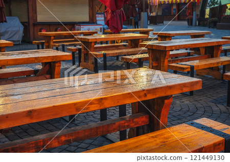wet wooden tables and benches in a street cafe in evening in the rain 121449130
