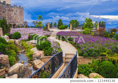 a fabulously beautiful blooming garden with a bridge over a stream, paths, bushes and flower beds. 121449136