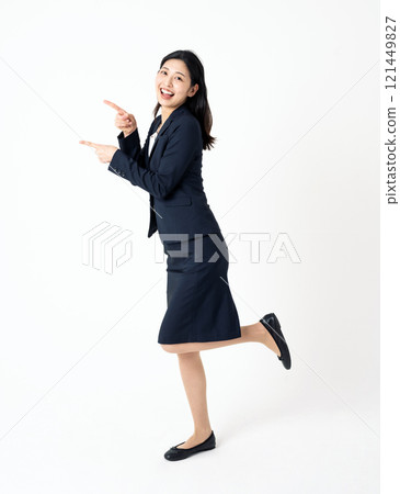 一位身穿西裝的年輕女子指向側面的全身肖像 121449827