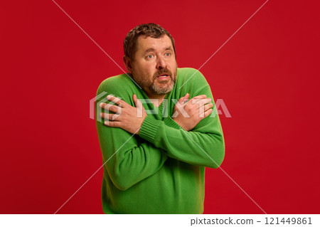 Man crossing arms over chest, shivering, demonstrating chills or fever, common symptoms of viral infections like flu or colds. Man crossing arms over chest, shivering, demonstrating chills or fever, common symptoms of viral infections like flu or colds. 121449861