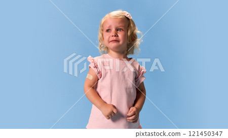Little child in light pink clothing looking worried with slight tearful expression against blue studio background. Little child in light pink clothing looking worried with slight tearful expression against blue studio background. 121450347