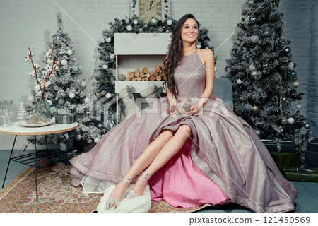 Radiant Woman Sitting with Tiara in Festive Decor. Radiant Woman Sitting with Tiara in Festive Decor. 121450569