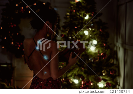 Backlit Woman with Gift near Christmas Tree. 121450724
