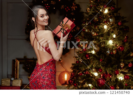 Woman in Backless Red Dress with Gift Box. Woman in Backless Red Dress with Gift Box. 121450740
