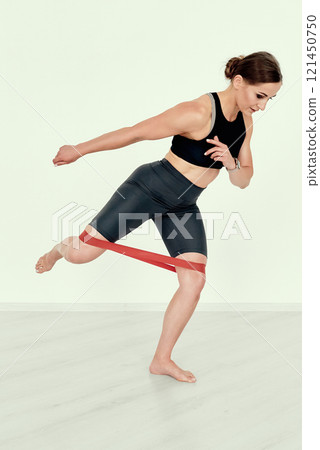 Fitness Trainer Demonstrating Dynamic Resistance Band Exercise 121450750