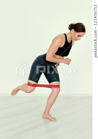 Fitness Trainer Performing Resistance Band Kickback Exercise 121450752