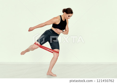 Fitness Trainer Demonstrating Side Leg Lift with Resistance Band 121450762