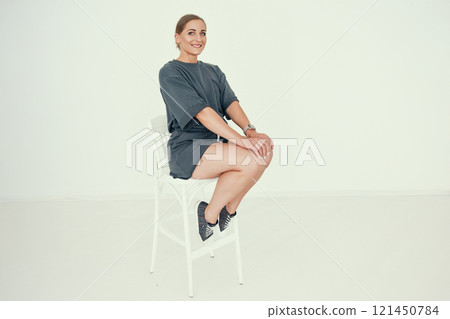 Smiling Fitness Trainer Sitting on a Chair in Casual Outfit 121450784
