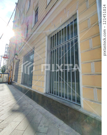 A close-up view of a beige building with wooden-framed windows and weathered surfaces. This photo reflects the impact of time and urbanization on architectural heritage. 121451814