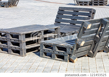 Creative outdoor seating arrangement made of wooden pallets in a sunny urban environment Creative outdoor seating arrangement made of wooden pallets in a sunny urban environment 121453525