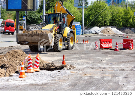 Construction crew works on road improvements in bright daylight near urban landscape. Copy space. Construction crew works on road improvements in bright daylight near urban landscape. Copy space. 121453530