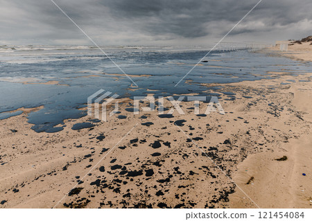 Oil leak in coastline after a tanker wreck. Fuel oil polluted beach Oil leak in coastline after a tanker wreck. Fuel oil polluted beach 121454084