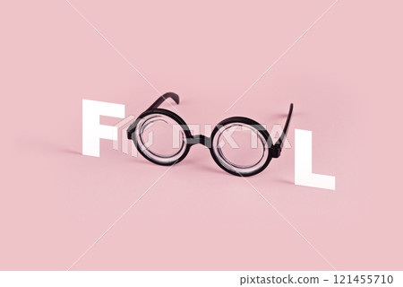 Round black glasses with F and L letters forming word Fool, placed on pastel pink background, combining humor and minimalism Round black glasses with F and L letters forming word Fool, placed on pastel pink background, combining humor and minimalism 121455710