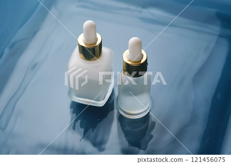 Bottle with white moisturizing serum in water on blue background. 121456075