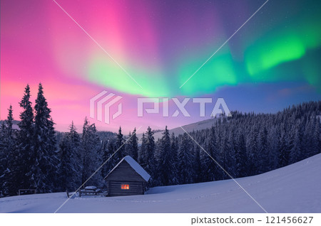 Small wooden cabin in snowy mountains under incredible Northern lights 121456627
