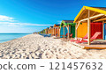 Colorful beach huts line a pristine, sandy shore under a vibrant blue sky. 121457632