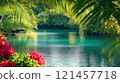 Serene turquoise lagoon viewed through lush tropical foliage, vibrant red flowers in foreground. 121457718