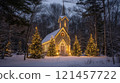 A snow-covered chapel in a winter forest, illuminated with Christmas lights on trees. 121457722