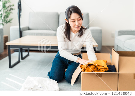 Young woman packing clothes Young woman packing clothes 121458043