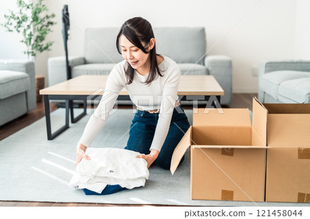 Middle-aged woman sorting out old clothes Middle-aged woman sorting out old clothes 121458044