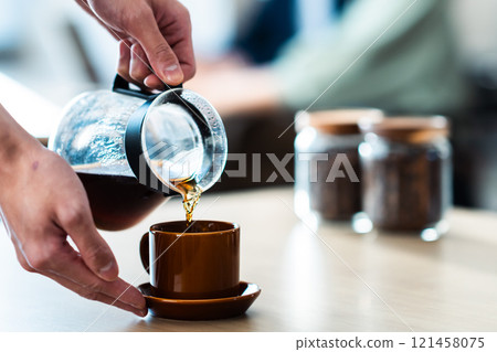 A calm cafe and a person brewing coffee, no face 121458075