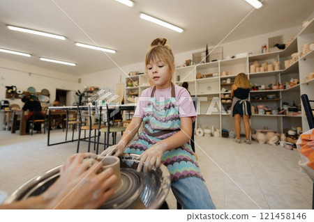 Girl enjoys pottery lessons in a bright studio during the afternoon Girl enjoys pottery lessons in a bright studio during the afternoon 121458146