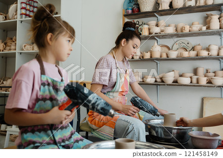 Mother and daughter crafting pottery together in a cozy studio Mother and daughter crafting pottery together in a cozy studio 121458149