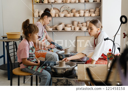Pottery workshop with children and adults creating clay art in a studio 121458158