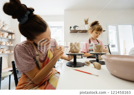 Mother and daughter creating pottery together in a cozy studio setting Mother and daughter creating pottery together in a cozy studio setting 121458163
