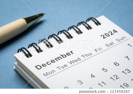 December 2024 - small spiral desktop calendar against abstract paper landscape, time and business concept 121458387