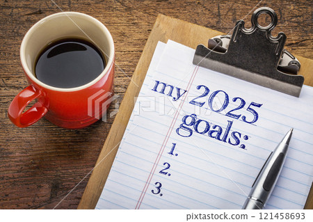 my 2025 goals list on clipboard and coffee against grunge wood desk, setting New Year goals and resolutions 121458693