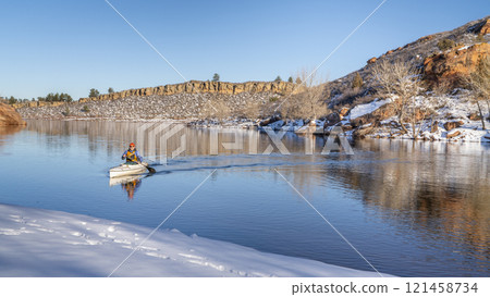 senior male wearing life jacket is paddling expedition canoe in winter scenery of Horsetooth Reservoir in northern Colorado 121458734