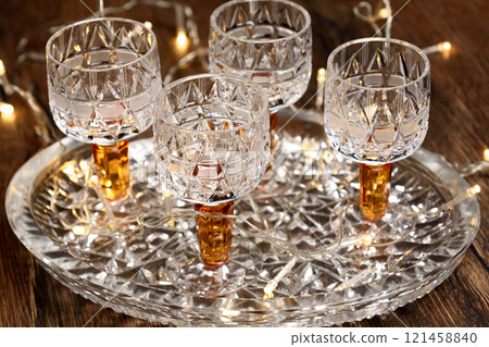Close up of crystal wine glasses on crystal tray and Christmas garland. 121458840