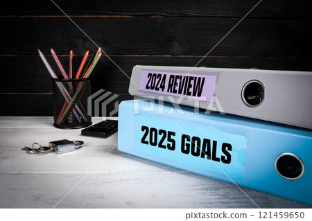 2024 Review and 2025 Goals. Two binders on desk in the office. Business background 2024 Review and 2025 Goals. Two binders on desk in the office. Business background 121459650