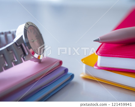 A notebook and a clock on the table 121459941
