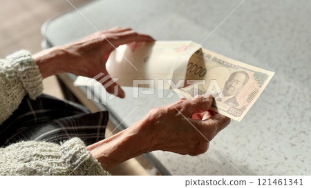 Elderly woman putting new 10,000 yen bills into a New Year's gift envelope Elderly woman putting new 10,000 yen bills into a New Year's gift envelope 121461341