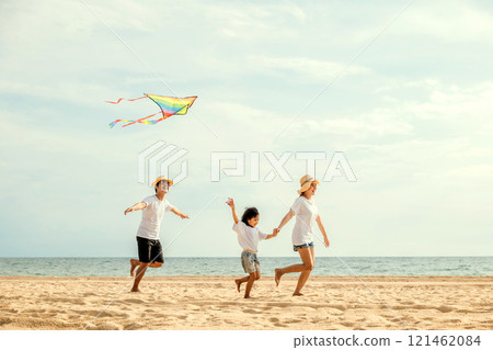 Asian family is flying a kite high in the sky while running on the beach. Happy parents mother and father with their child playing with kite, family is enjoying their time together, summer day Asian family is flying a kite high in the sky while running on the beach. Happy parents mother and father with their child playing with kite, family is enjoying their time together, summer day 121462084