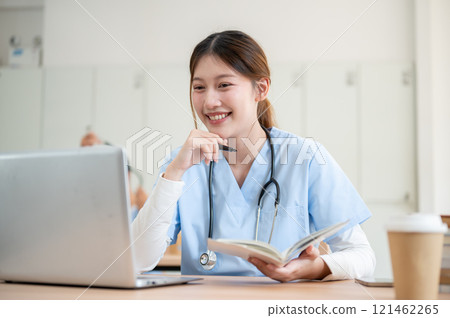 A smart Asian female medical student is focused on reading medical cases on her laptop. A smart Asian female medical student is focused on reading medical cases on her laptop. 121462265
