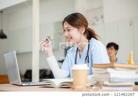 A smart Asian female medical student is focused on reading medical cases on her laptop. A smart Asian female medical student is focused on reading medical cases on her laptop. 121462267