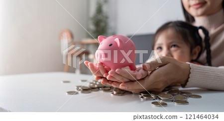 Mother and Daughter Bond Over Financial Planning with Piggy Bank Savings 121464034