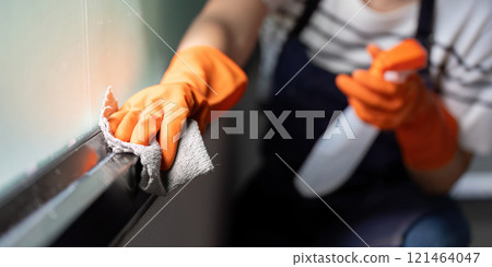 Woman in Gloves Scrubbing Window with Cloth and Spray 121464047