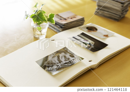 Album and stack of photo prints on a table Album and stack of photo prints on a table 121464118