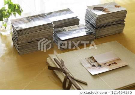 Album and stack of photo prints on a table Album and stack of photo prints on a table 121464150