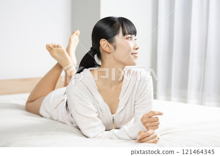 清晨穿著睡衣躺在床上的年輕女子 清晨穿著睡衣躺在床上的年輕女子 121464345