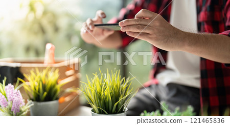 Modern Gardener Documenting Plant Growth with Smartphone Camera 121465836