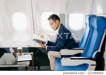 Young Asian executive excels in first class, multitasking with digital tablet, laptop and smartphone. Young Asian executive excels in first class, multitasking with digital tablet, laptop and smartphone. 121466685